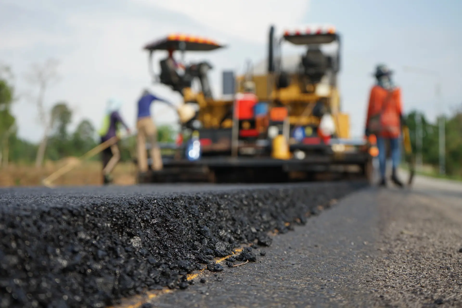 A close up view of freshly paved asphalt with the Mahaffey crew in the background